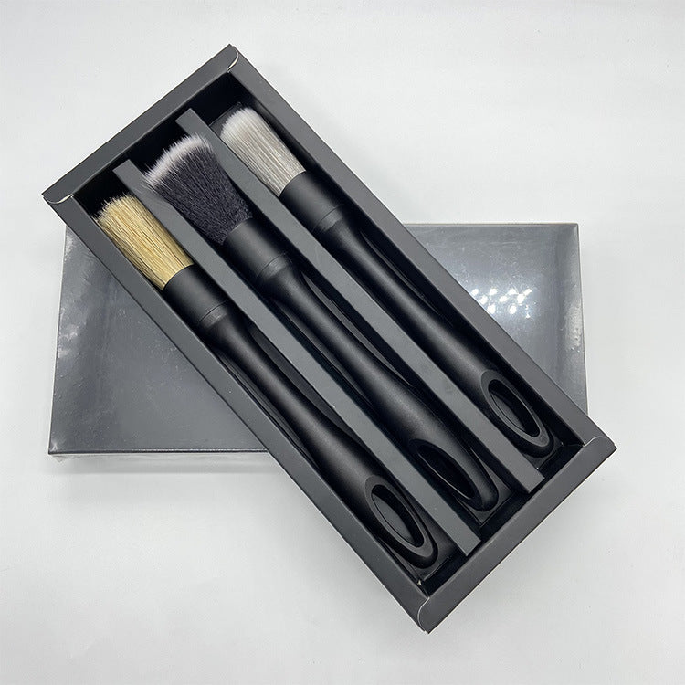 The three brushes lying in the compartments of their open drawer box, seen from above.