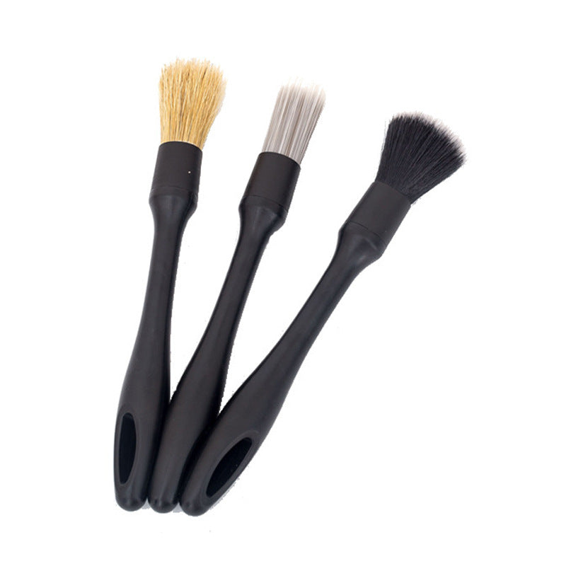 The three-piece interior detailing brush set: three brushes with black handles and pale tan, white and soft black bristle heads, on a white background.